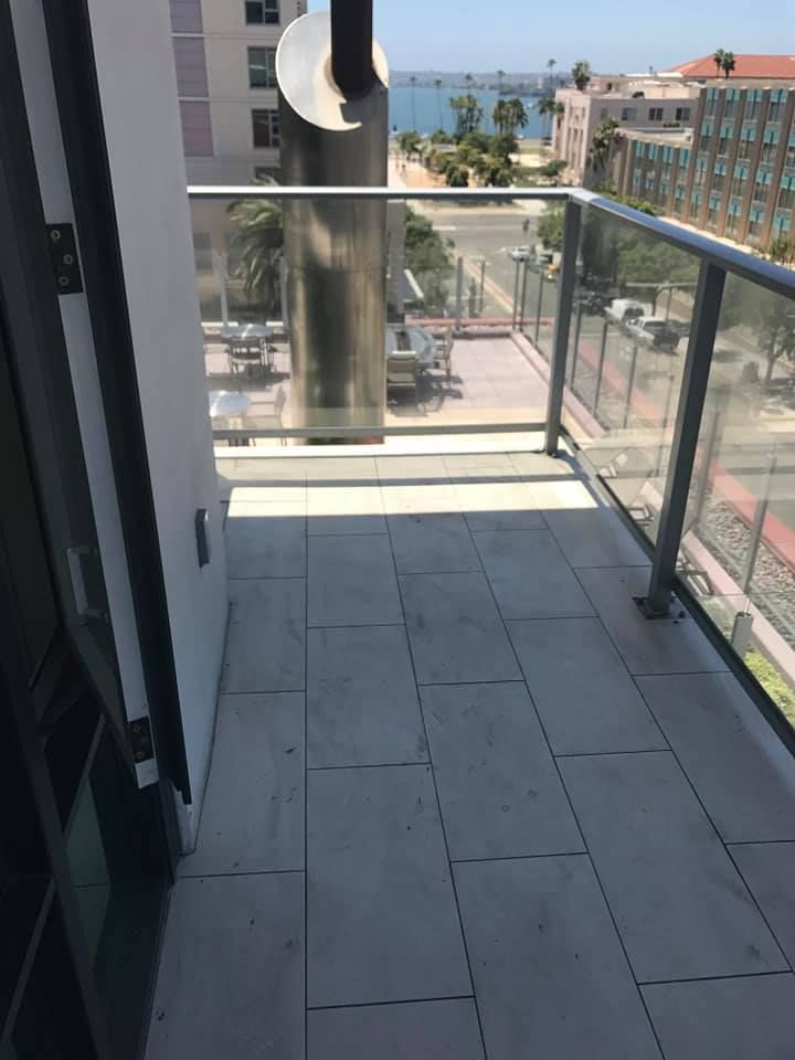 Balcony with tiled floor, glass railing, city and water view.