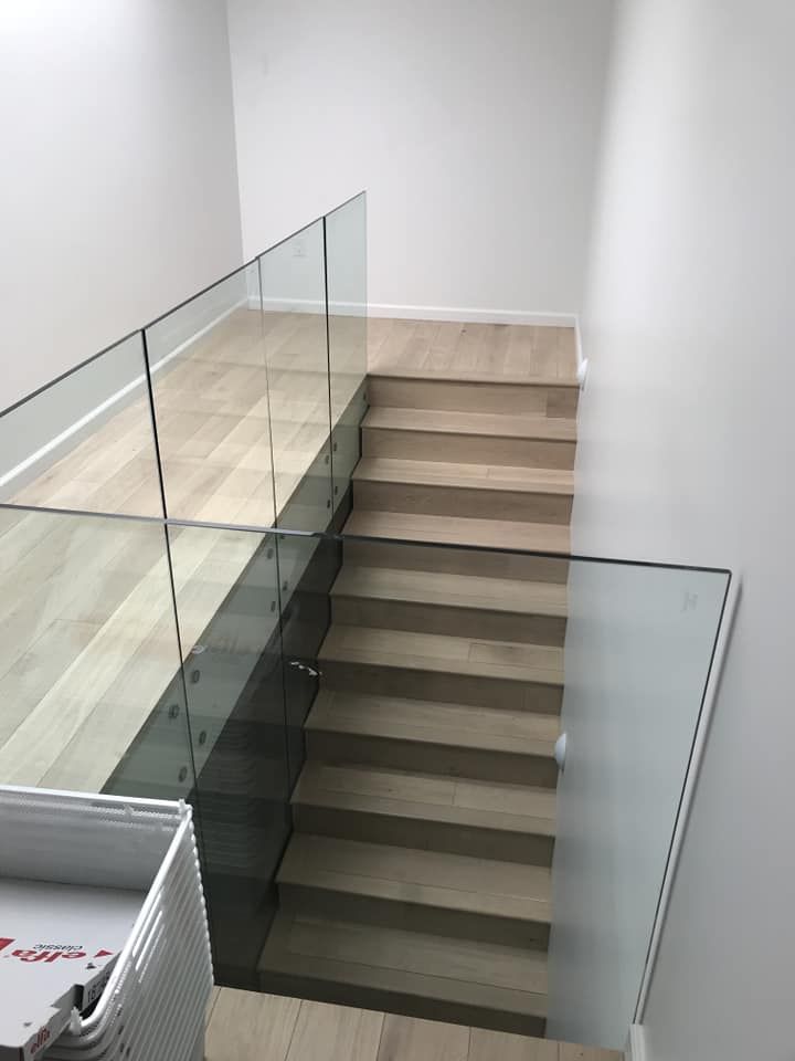 Modern wooden staircase with glass railing.