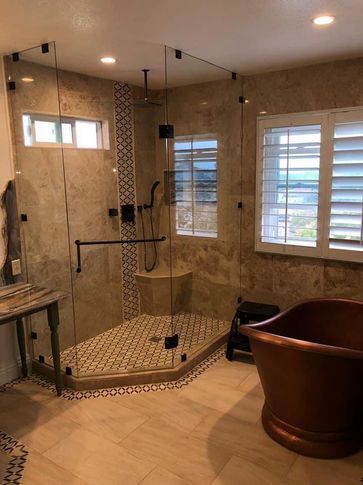 Bathroom with glass shower, brown tile, copper tub, and white shutters.