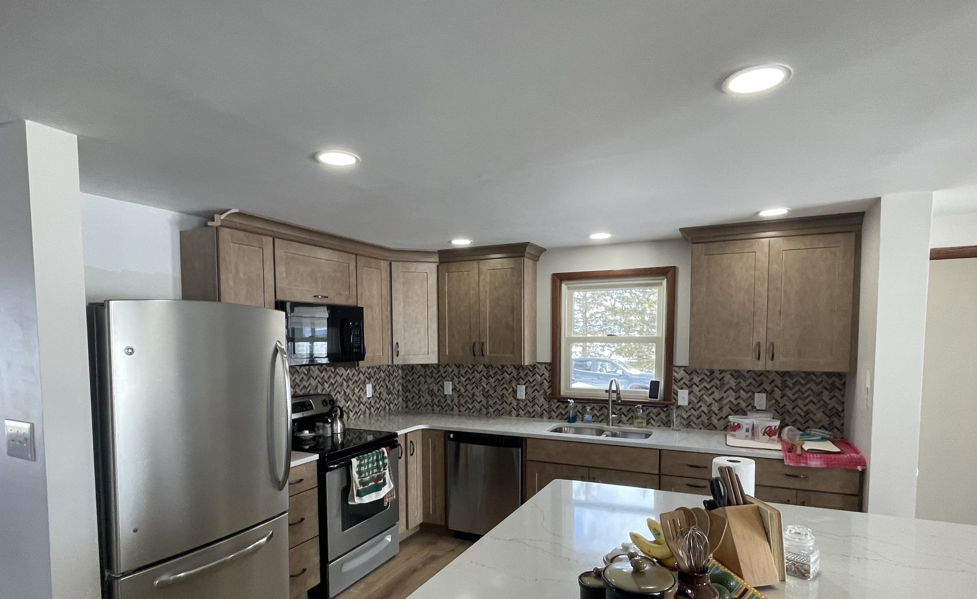 Modern kitchen with stainless steel appliances, wood cabinets, and a lighted island counter.