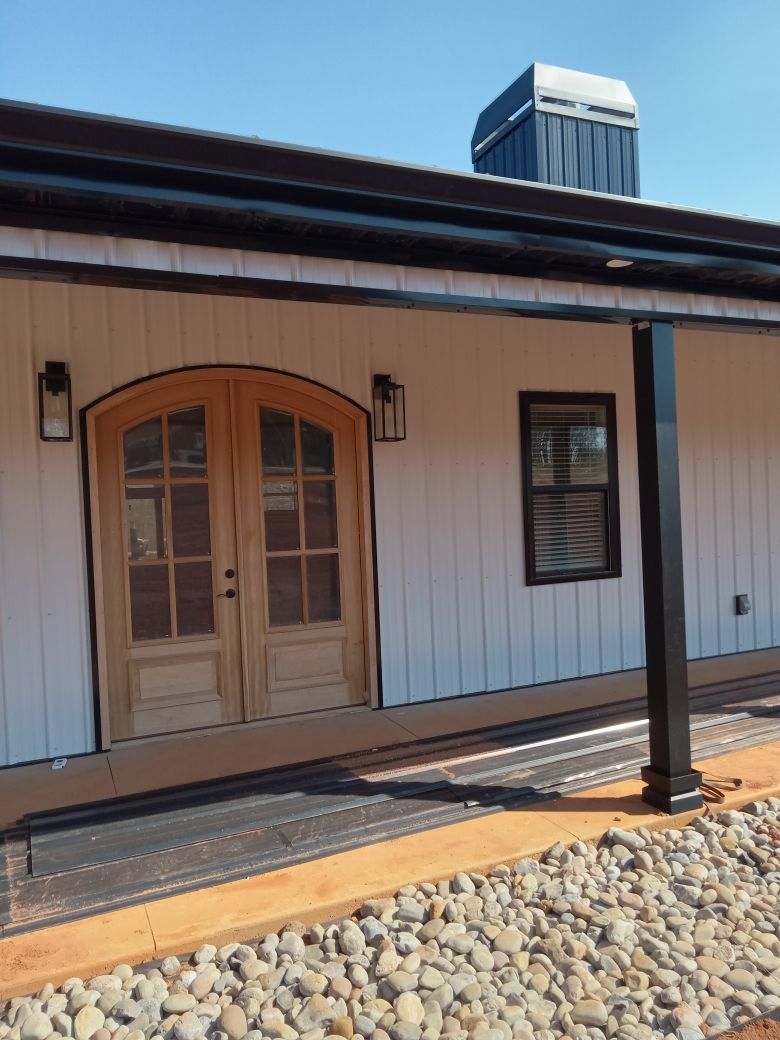 A white house with a porch and wooden doors.