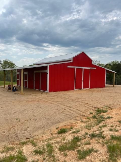 Side view of custom metal barn with wide overhangs and clean metal finishes.
