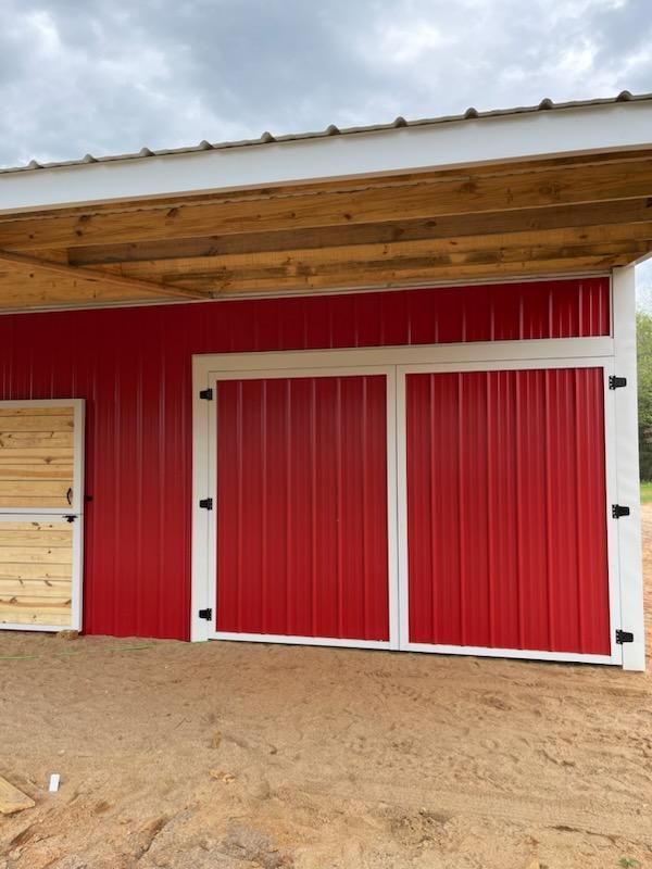 A red barn with white doors and a wooden roof