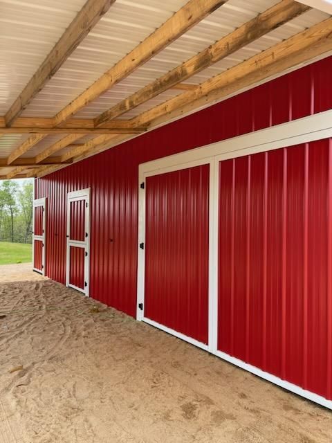Side view of durable metal barn with custom doors and exposed beam roofing.