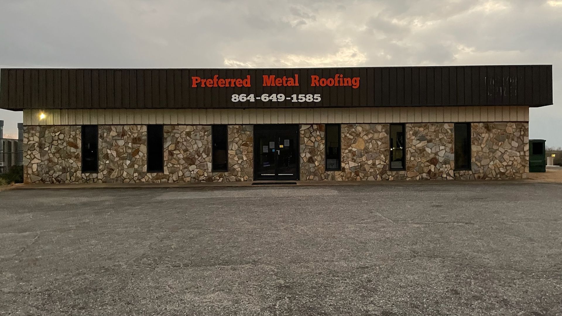 A preferred metal roofing building with a gravel driveway in front of it.