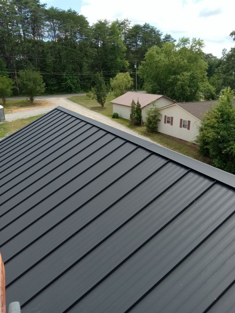 An aerial view of a black metal roof with a house in the background.
