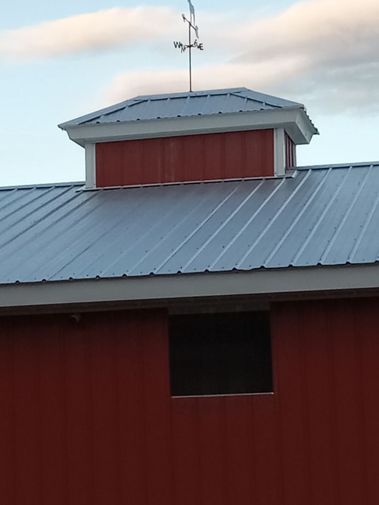 A red barn with a white roof and a weather vane on top.