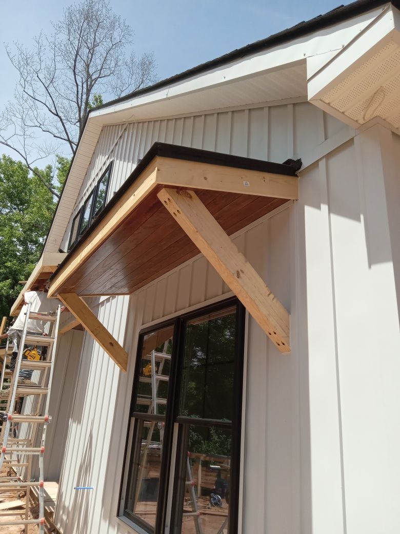 A white house with a wooden awning over a window.