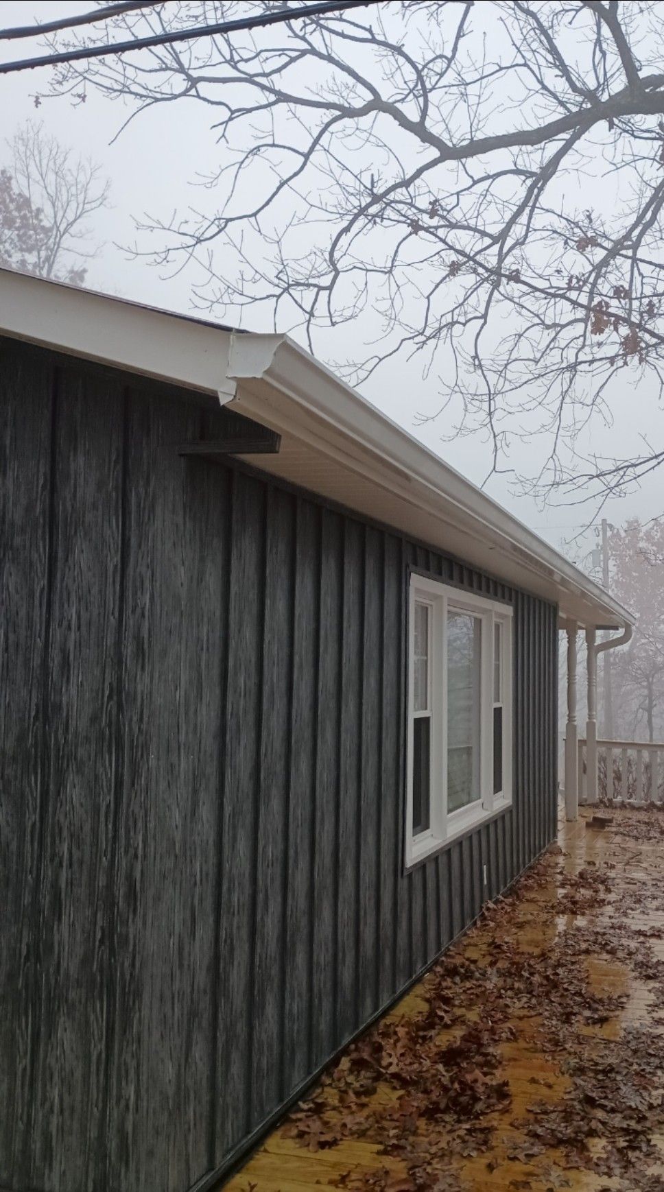 A house with a gray siding and a white window on a foggy day.