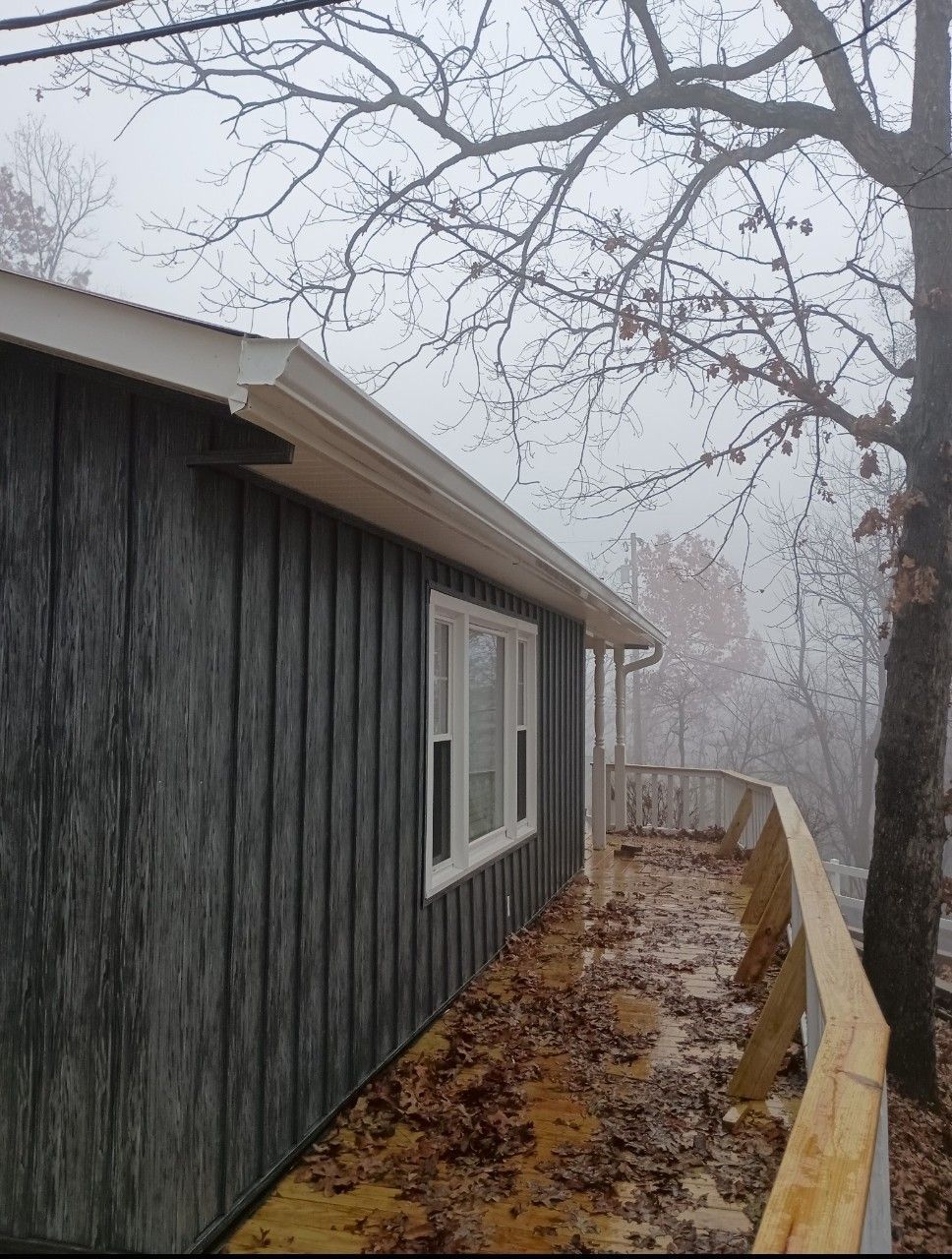 A house with a balcony and a tree in the background.