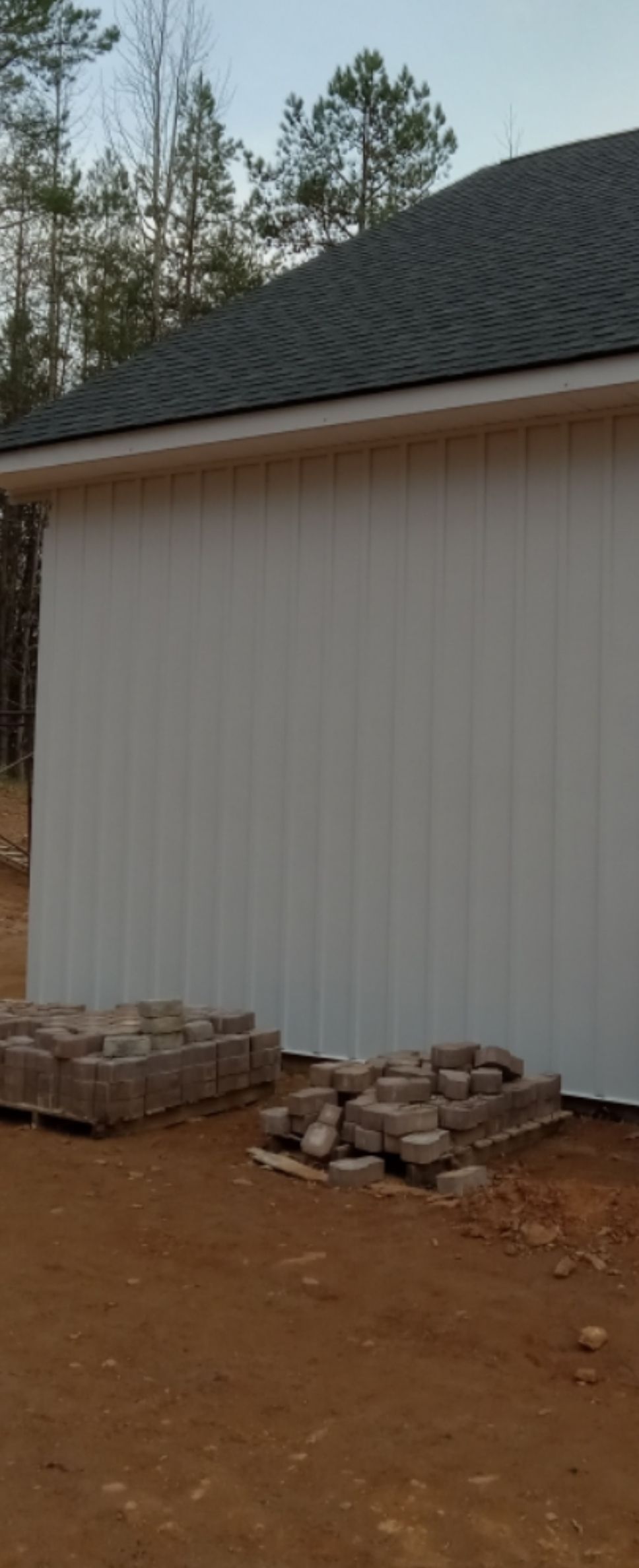A red barn with a white roof is sitting in the middle of a dirt field.