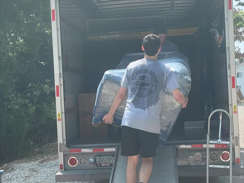 A man is loading a mattress into a truck.