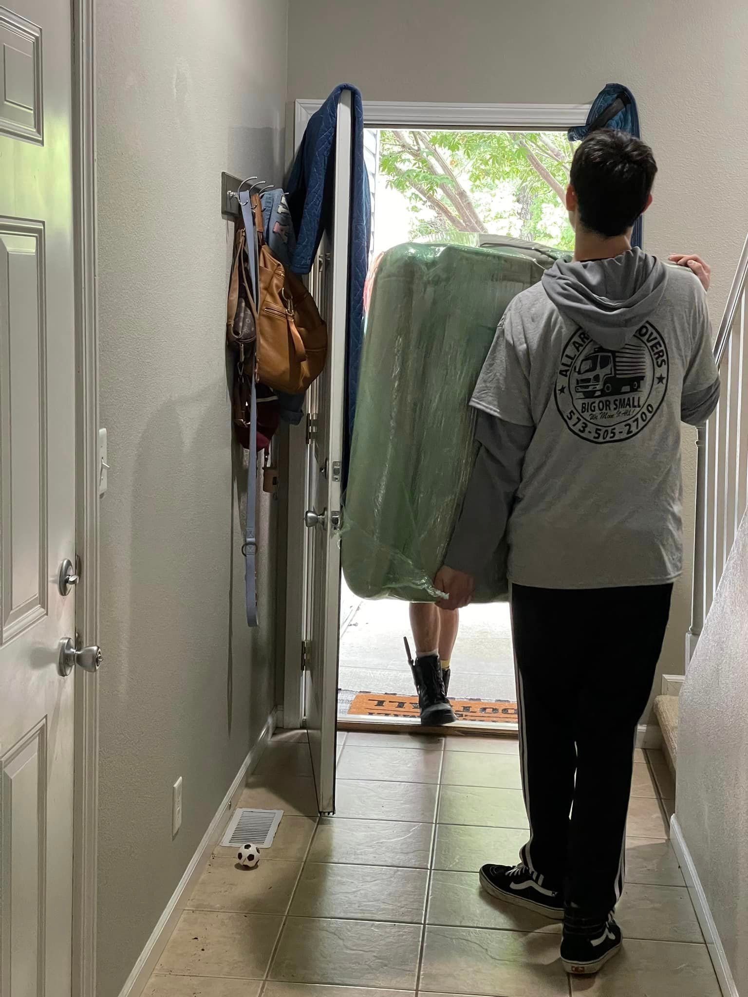 A man is carrying a mattress through a doorway.