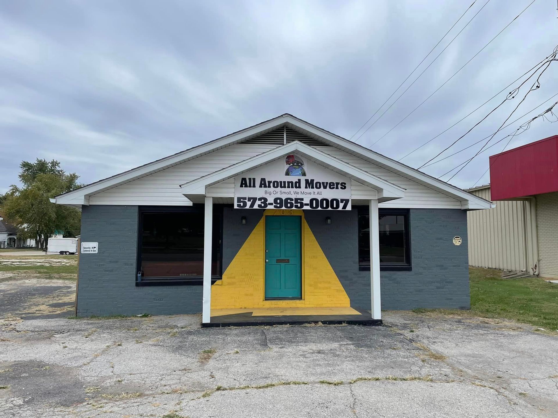 A gray and yellow building with a blue door and a phone number on it.