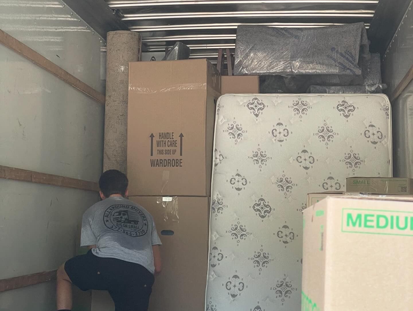 A man is loading a mattress into a moving truck.
