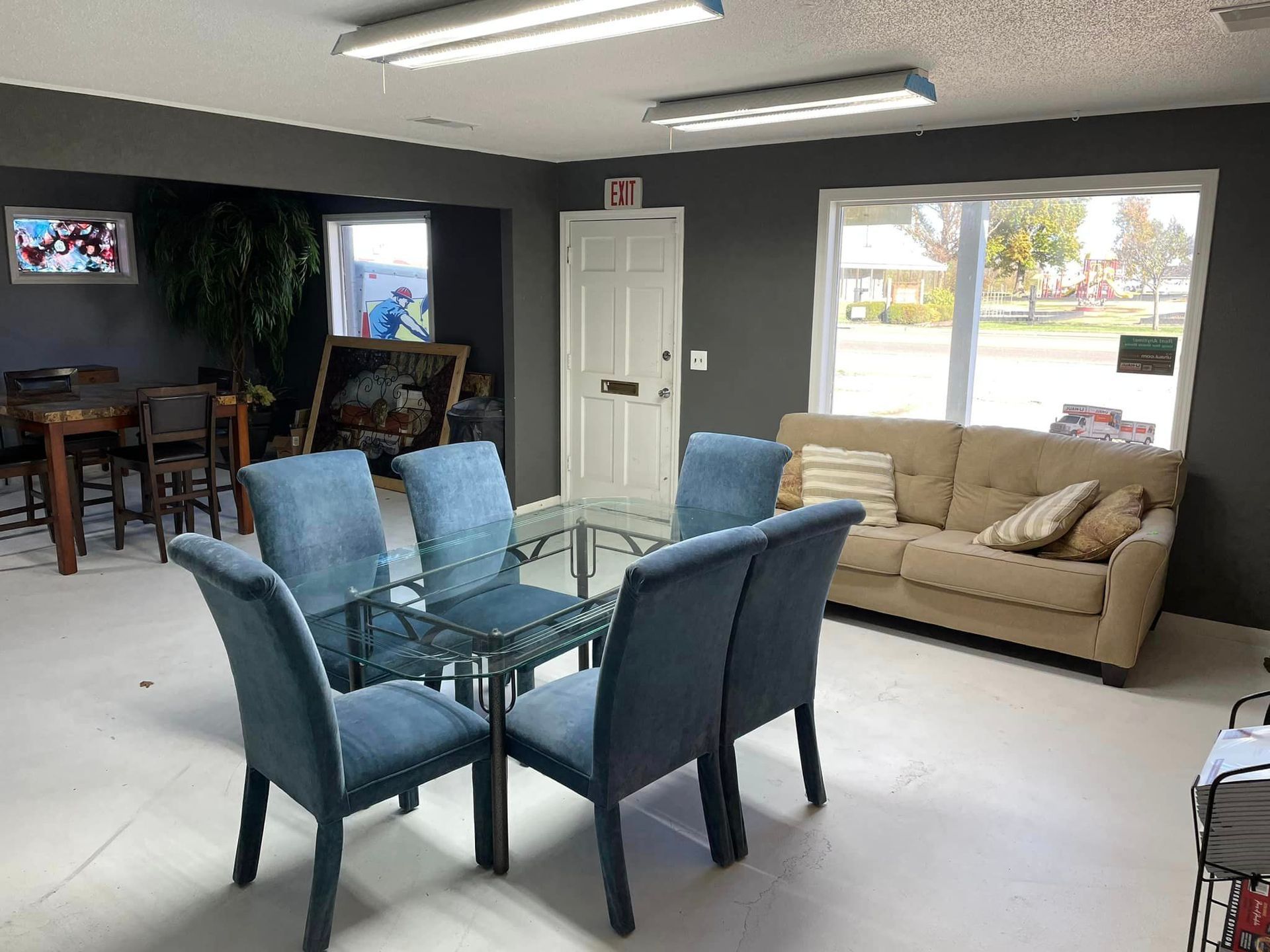 A living room with a couch , table , chairs and a glass table.