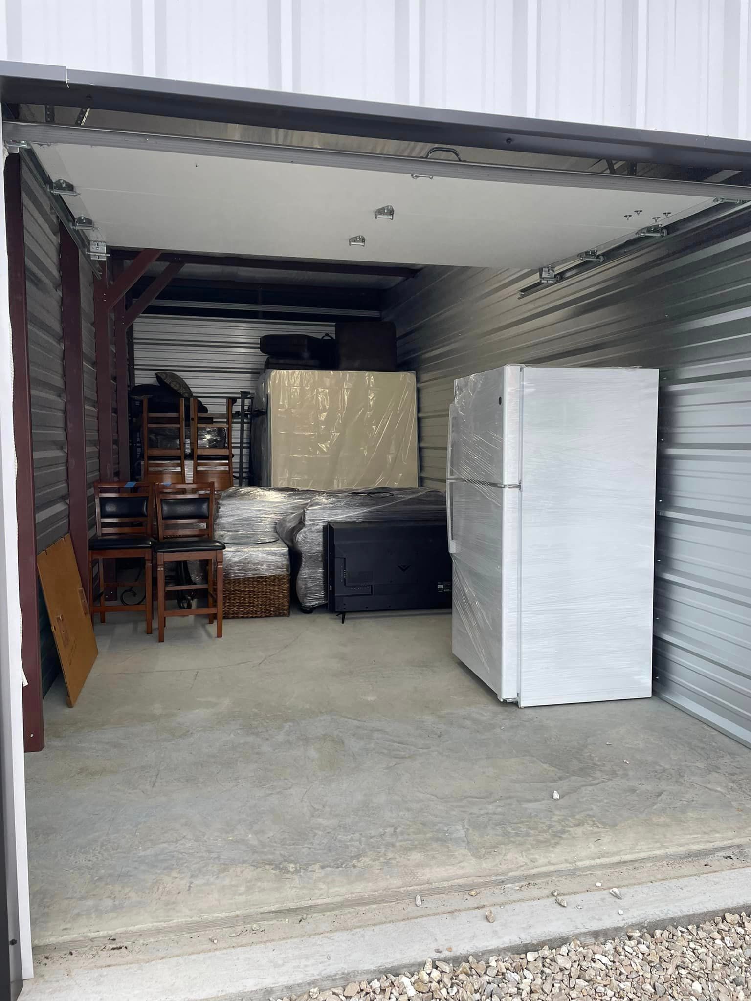 A storage unit filled with furniture and a refrigerator.