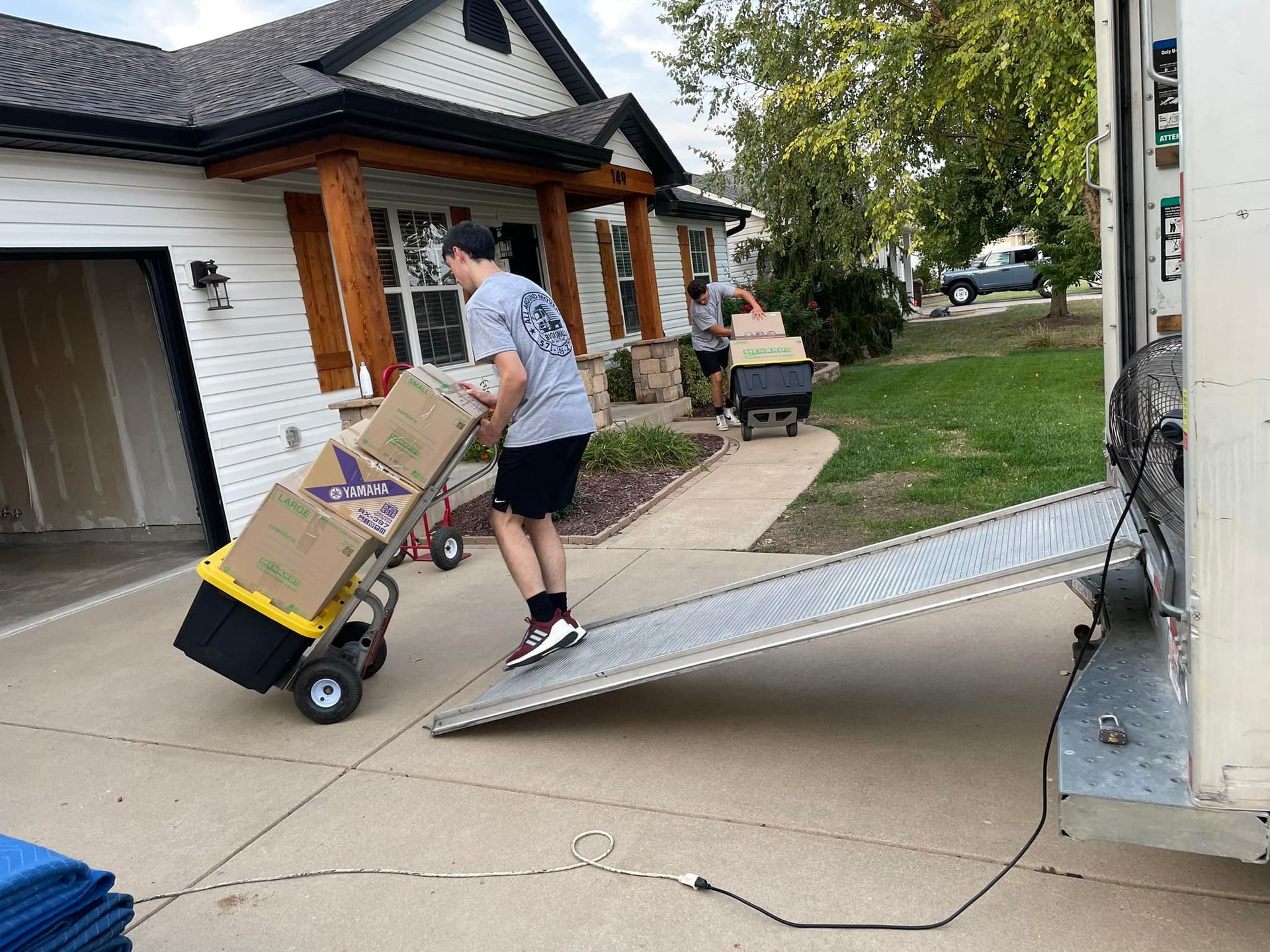 A man is pushing boxes on a dolly into a moving truck.