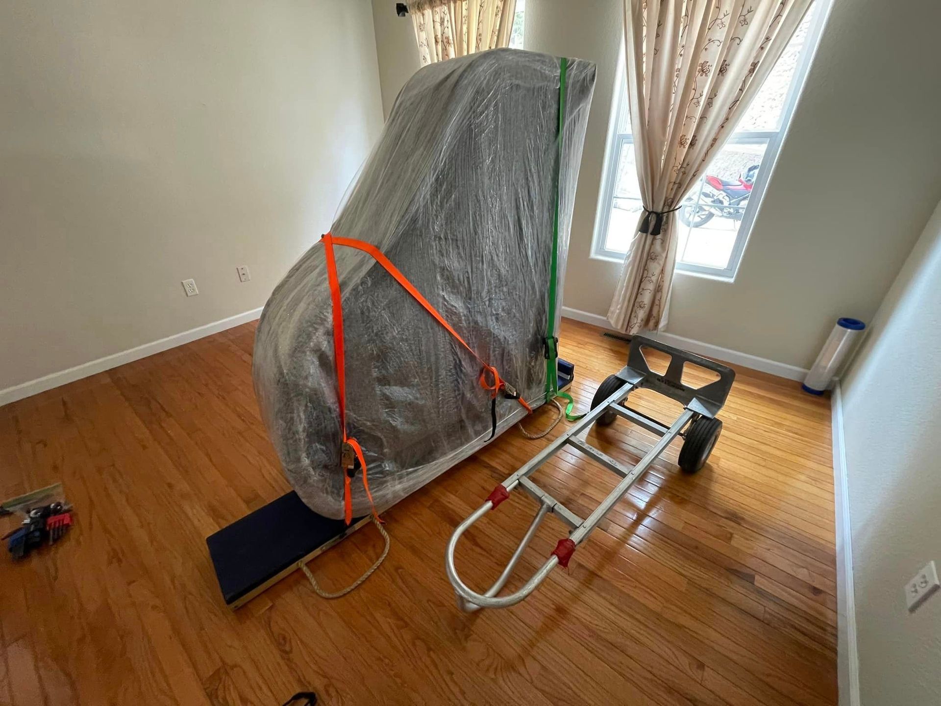 A piano is being moved in a room with a ladder.