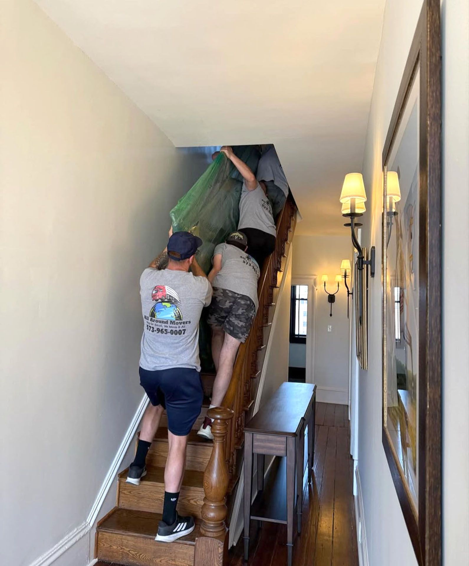 A group of men are moving a large piece of furniture up a set of stairs