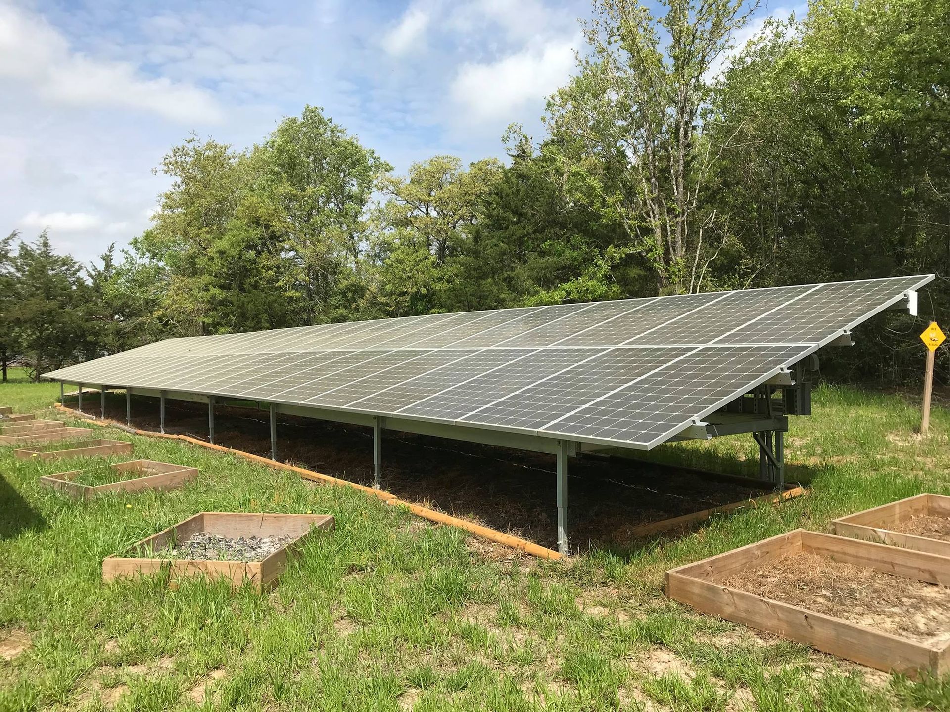 A row of solar panels sitting on top of a lush green field.