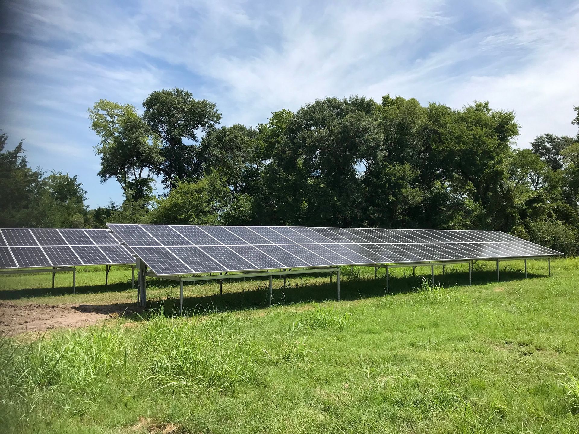 A row of solar panels are sitting in a grassy field.