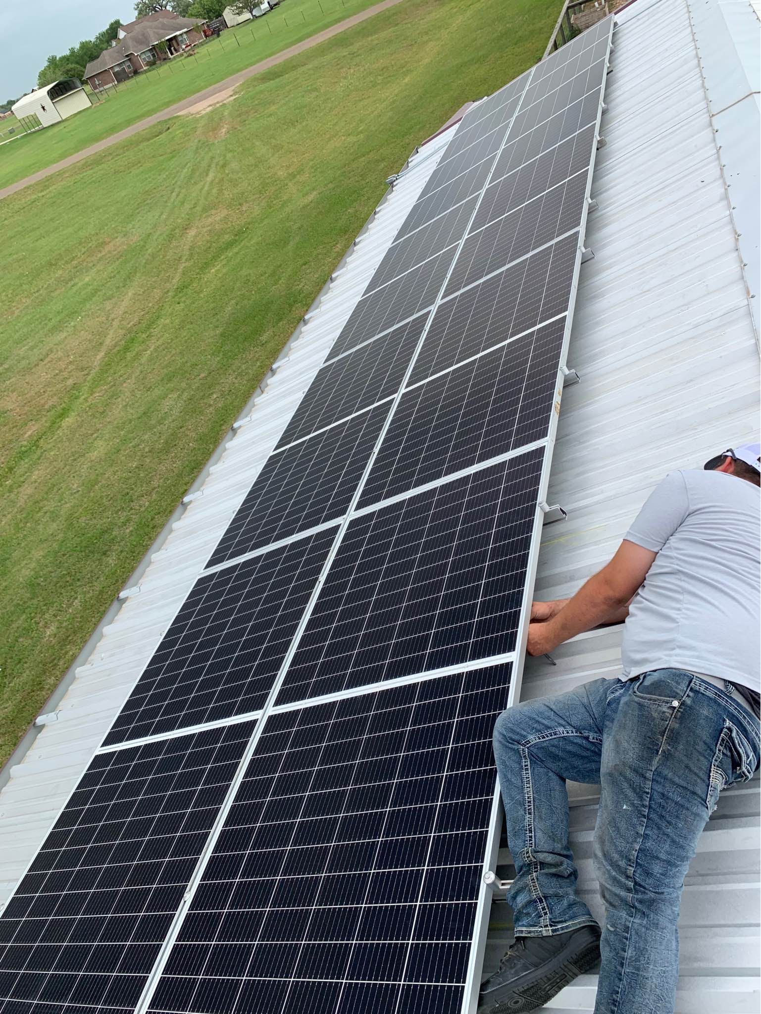 A man is installing solar panels on the roof of a building.