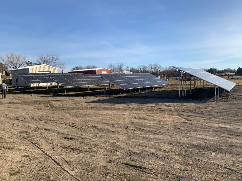 A row of solar panels are sitting on top of a dirt field.