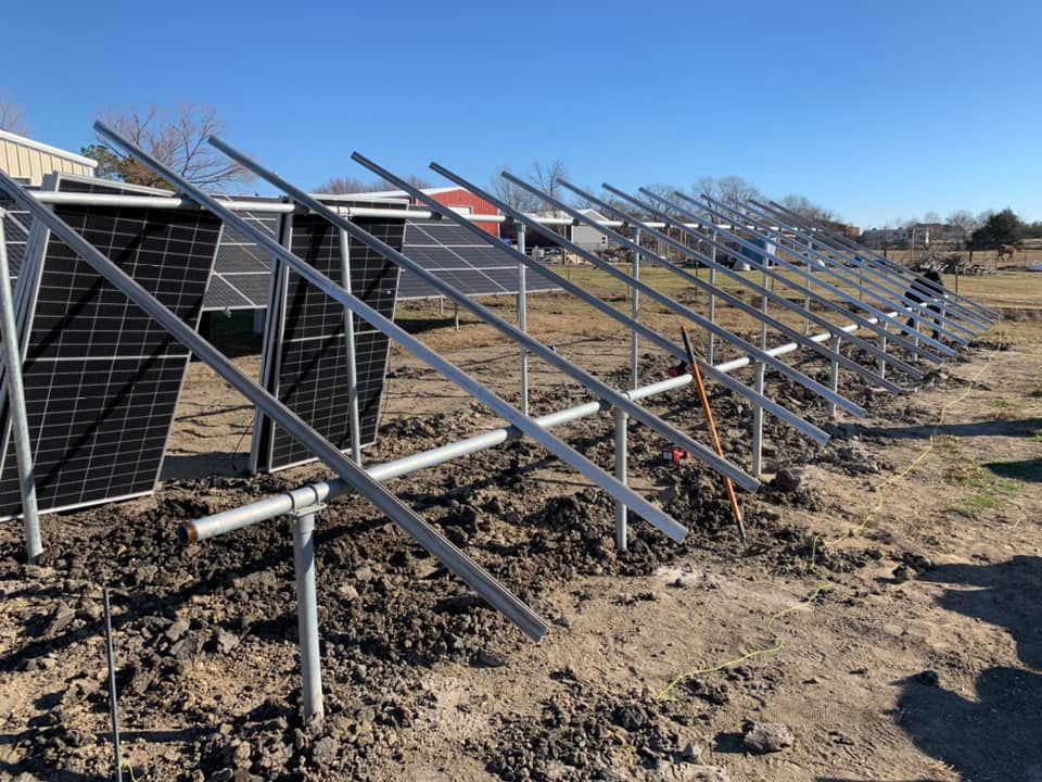 A row of solar panels sitting on top of a dirt field.