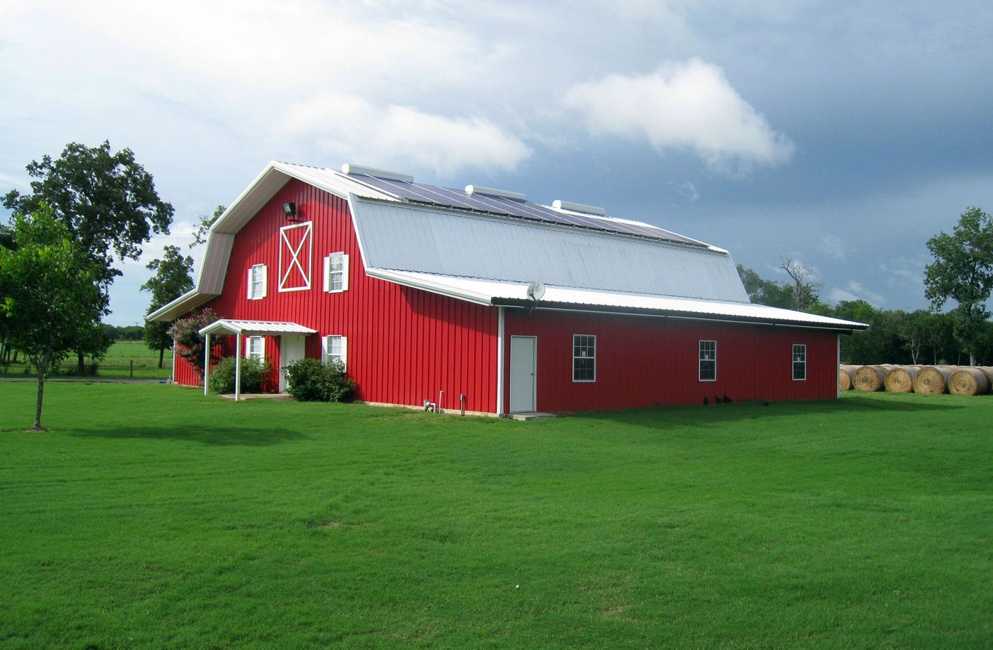 A large red barn is sitting in the middle of a grassy field