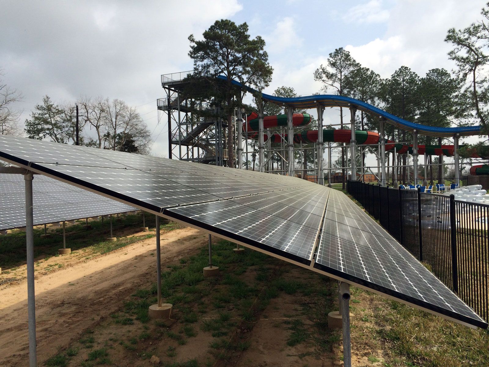 A row of solar panels are sitting in front of a water park.