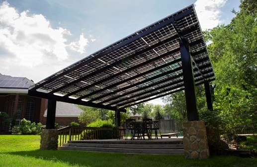 A pergola with solar panels on it is in the backyard of a house.