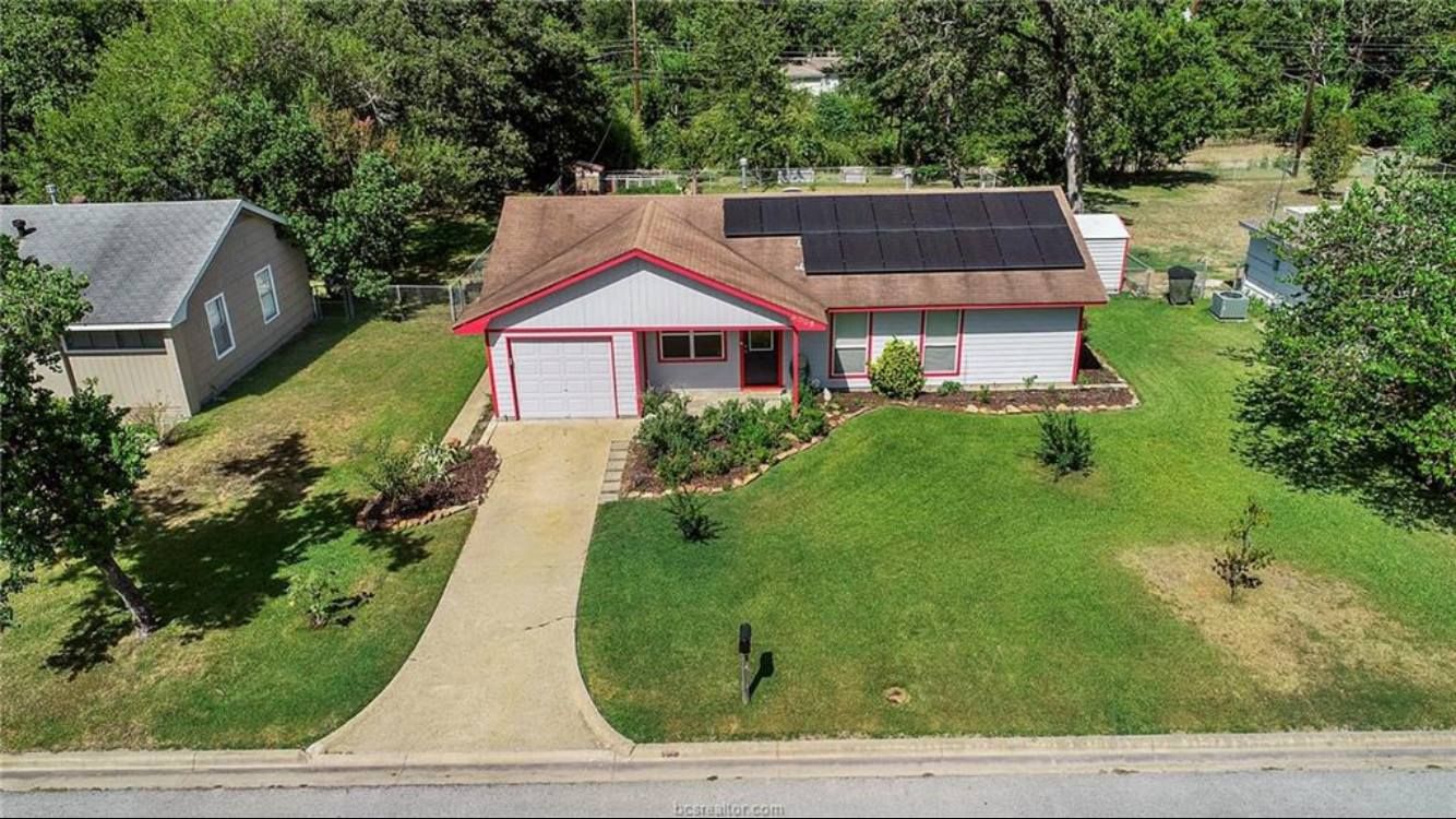 An aerial view of a house with solar panels on the roof.