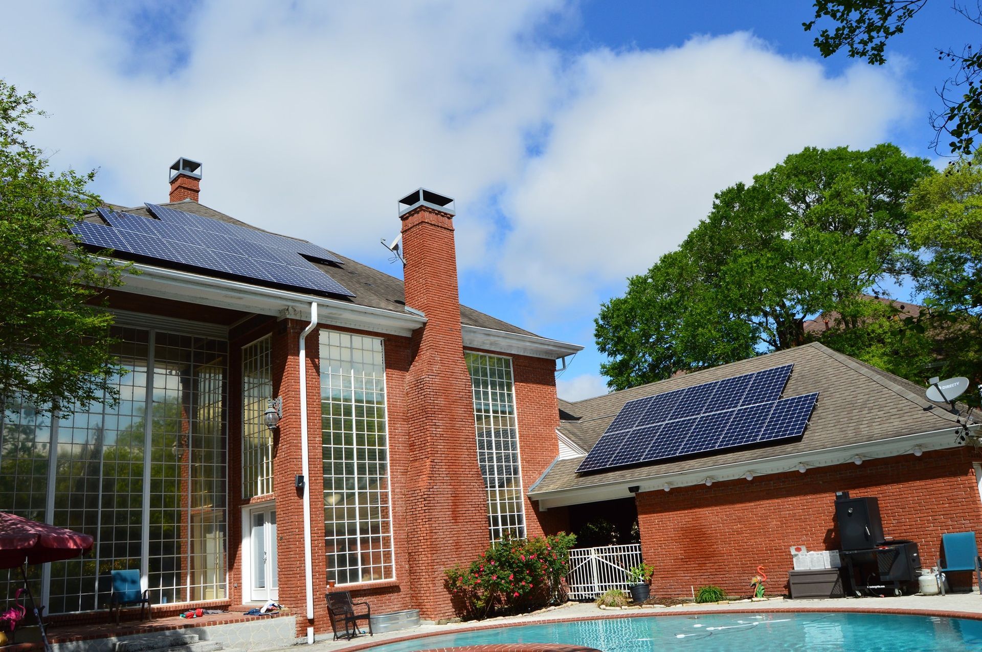 A brick house with solar panels on the roof and a swimming pool