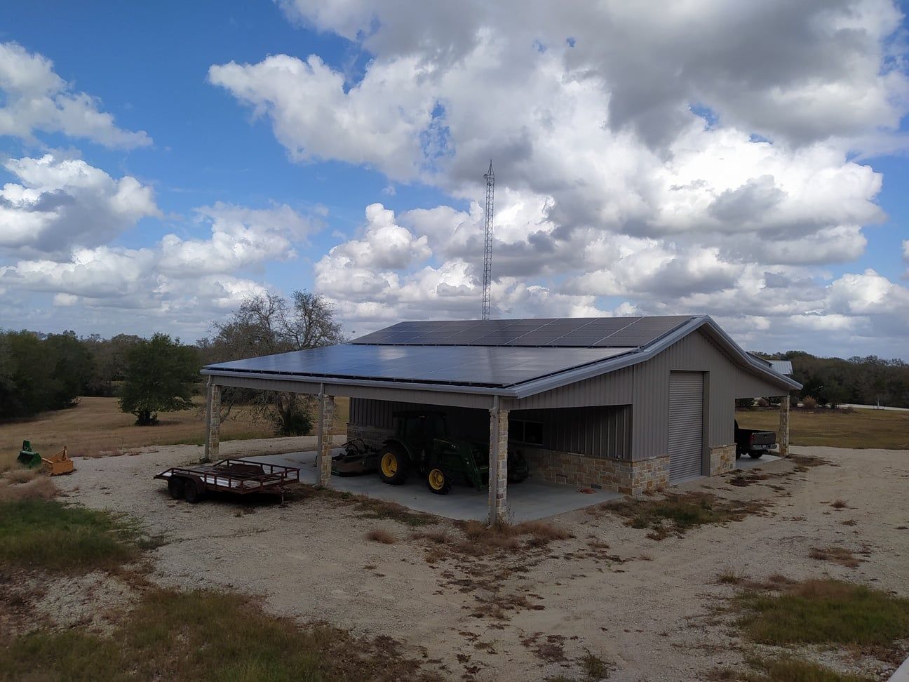 A tractor is parked in a garage with solar panels on the roof.