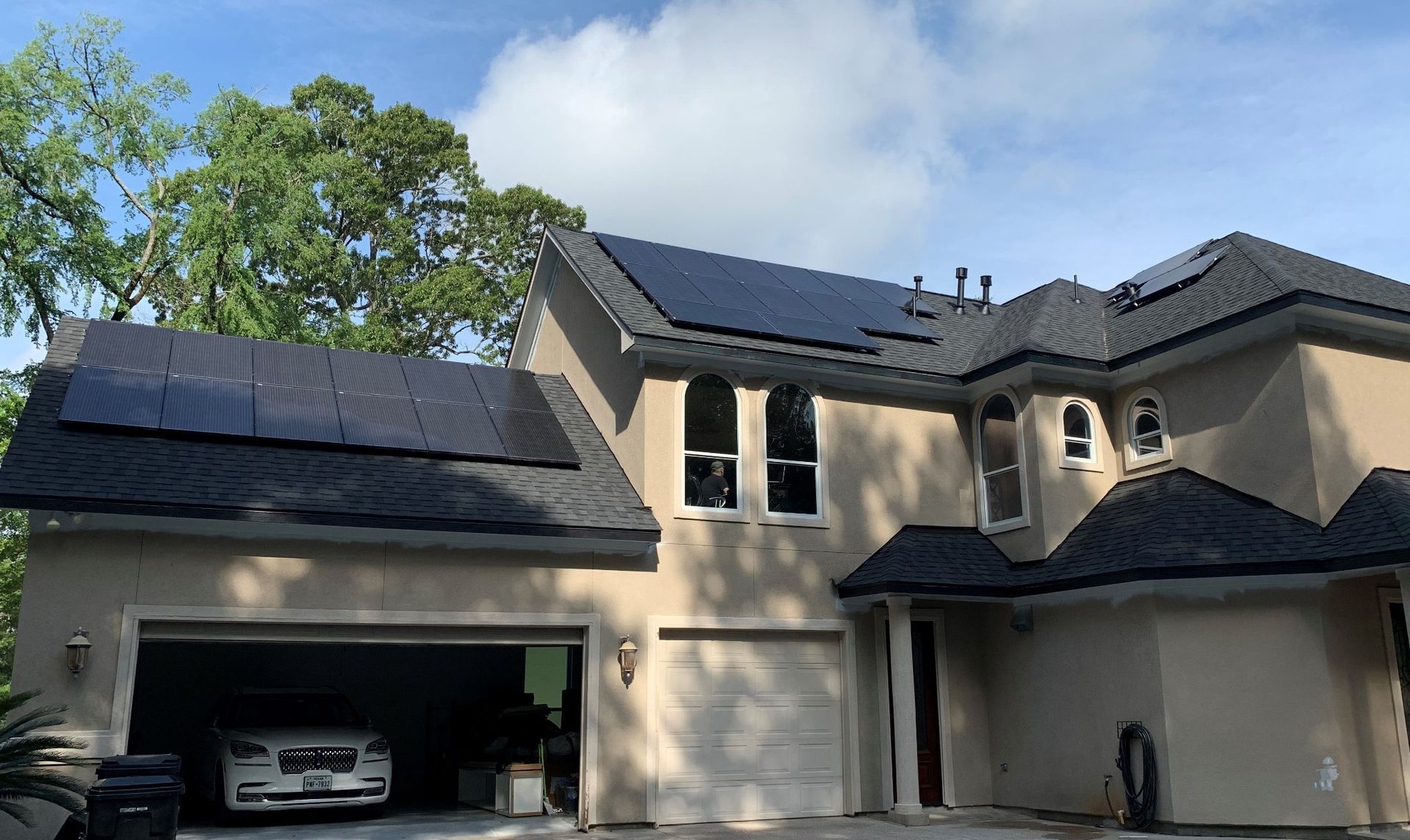 A house with solar panels on the roof and a car parked in the garage.