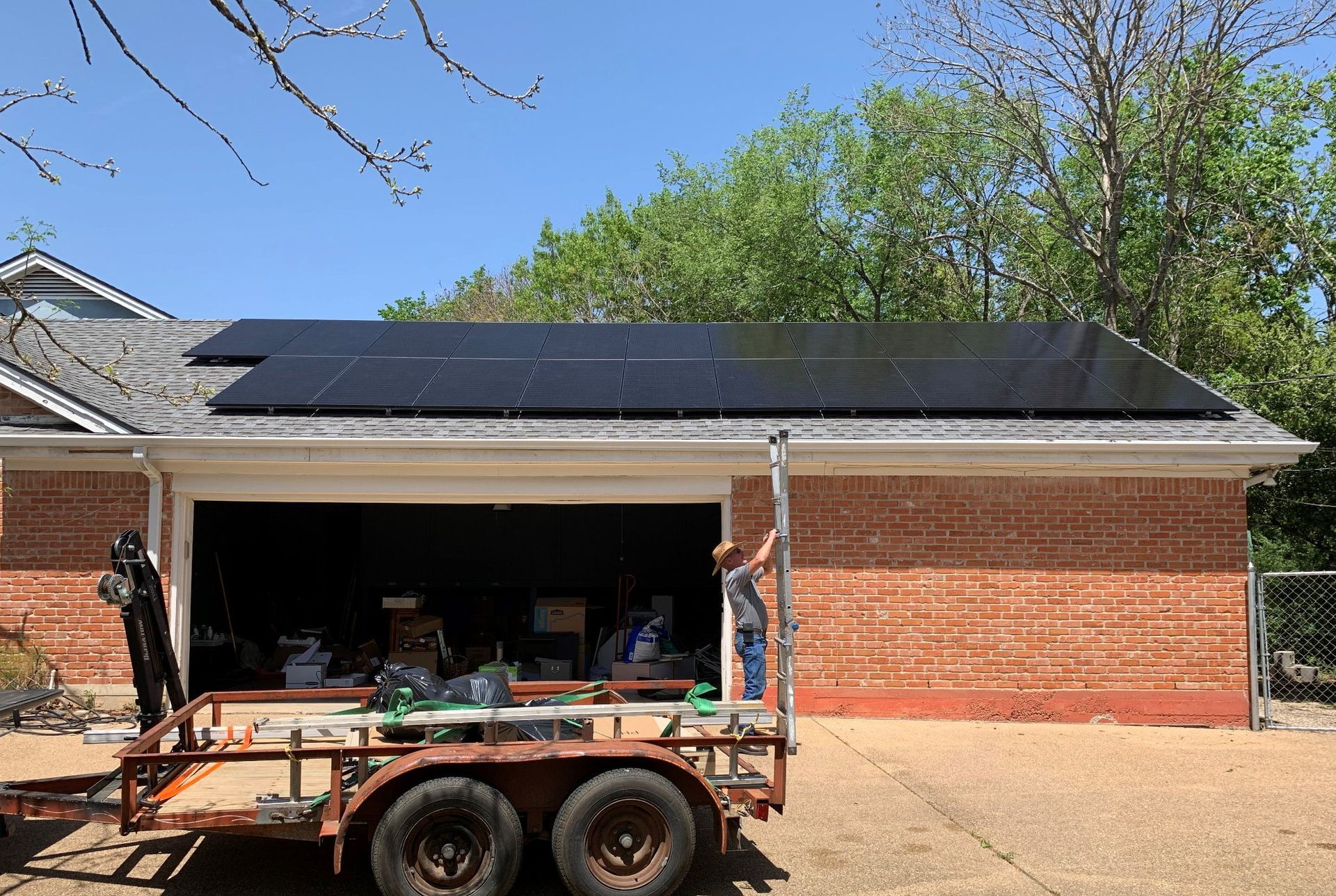 A man is installing solar panels on the roof of a house.