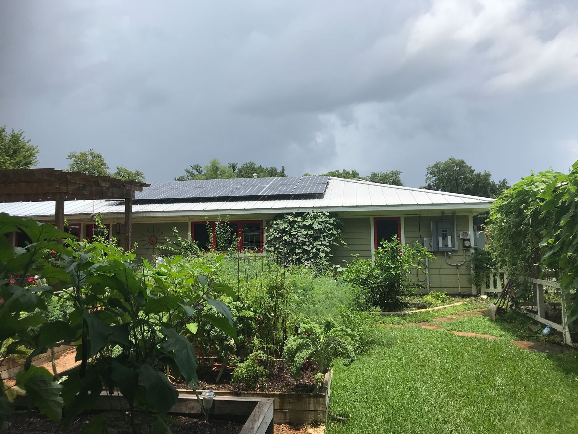 A house with solar panels on the roof and a garden in front of it.