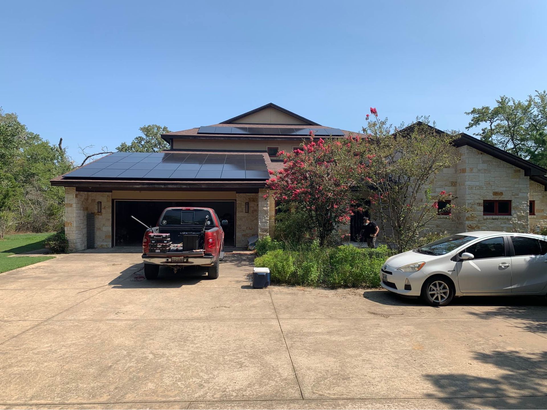 A red truck is parked in front of a house with solar panels on the roof.