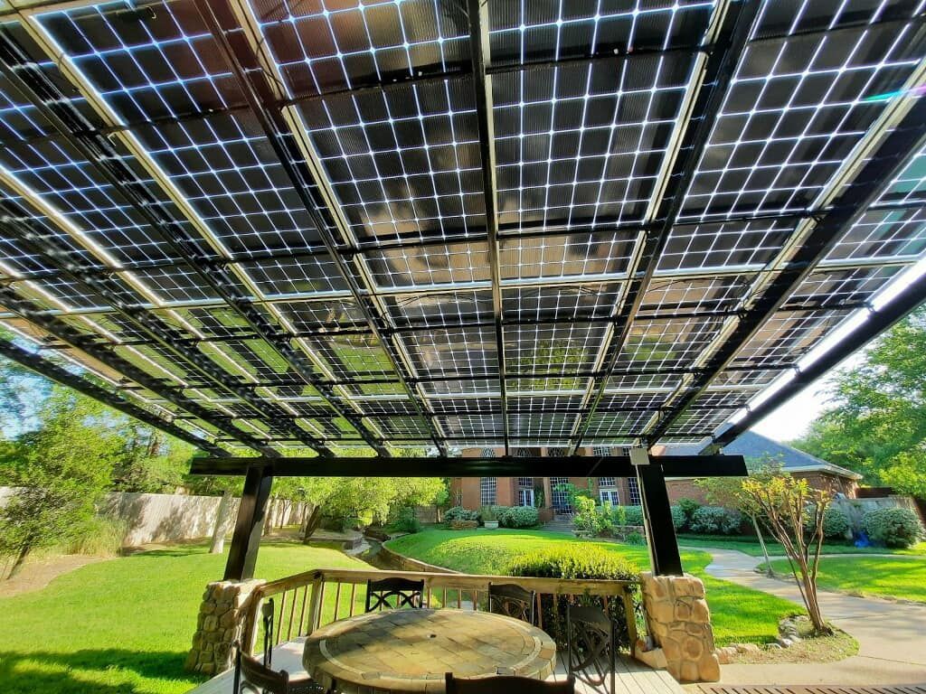 A patio with a table and chairs under a roof with solar panels.