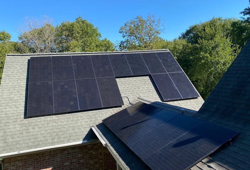 There are many solar panels on the roof of a house.