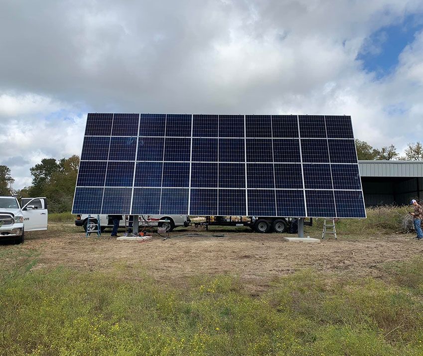 A large solar panel is sitting on top of a trailer in a field.
