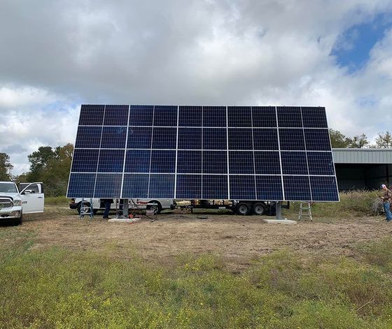 A large solar panel is sitting on top of a trailer in a field.