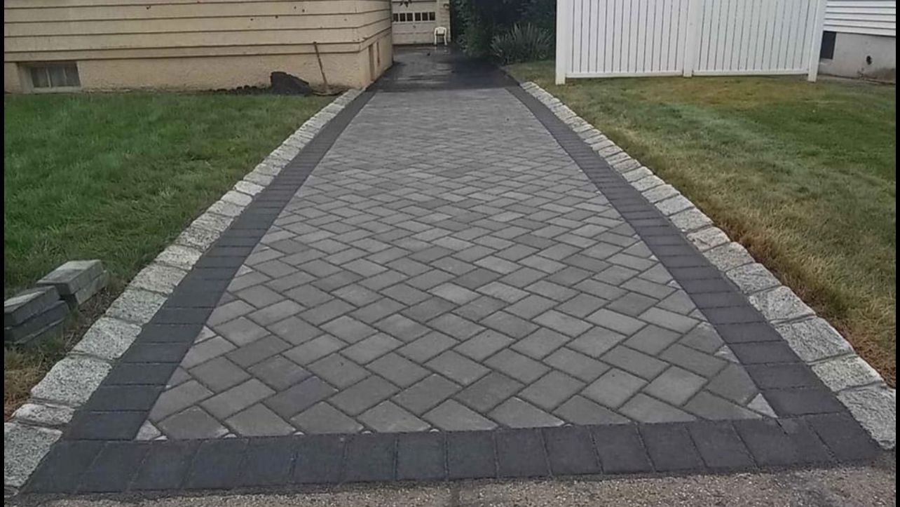 Brick pathway with gray and black borders and grassy edges.