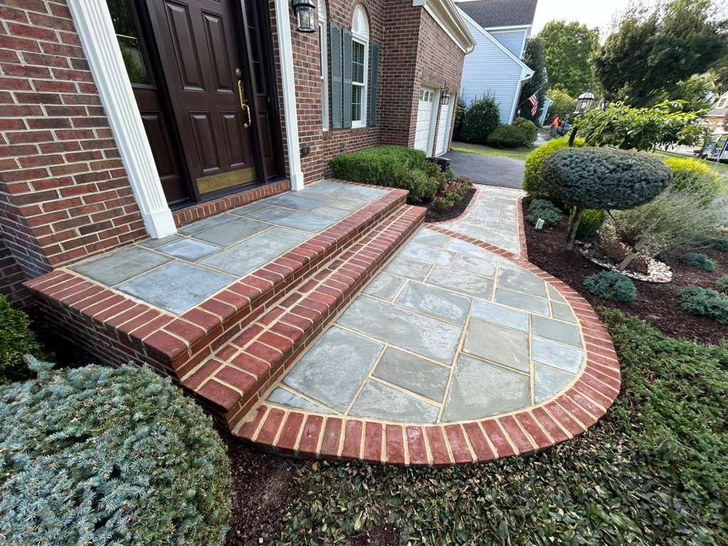 Brick and stone front entryway with steps and curved walkway.