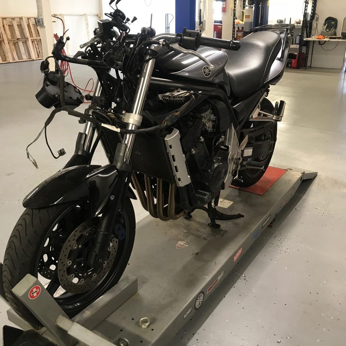 A motorcycle is sitting on a ramp in a garage.