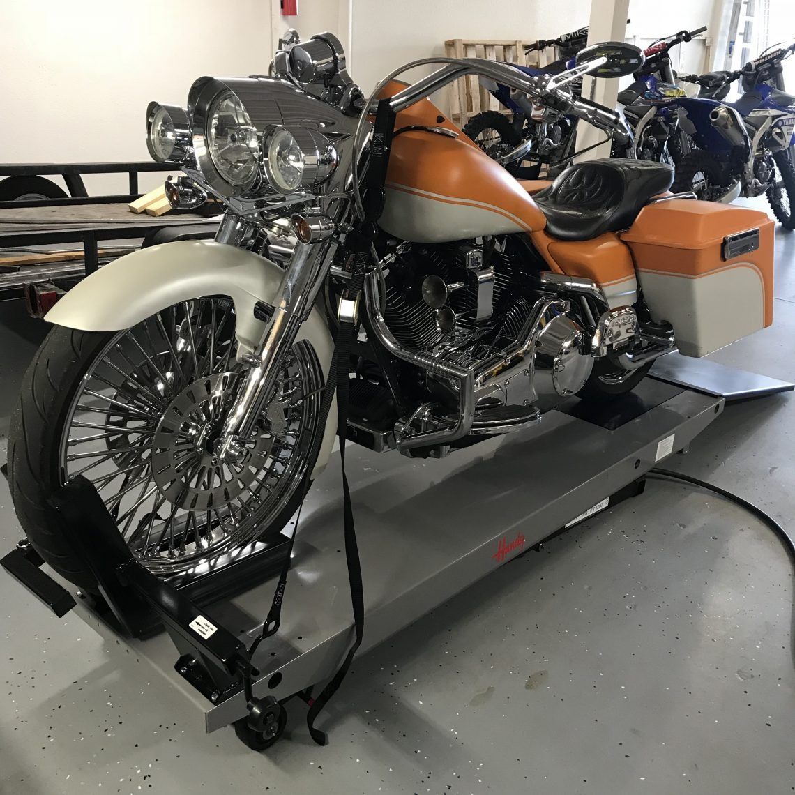 A harley davidson motorcycle is parked on a ramp in a garage.