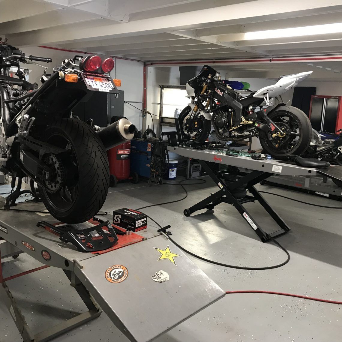 A motorcycle is sitting on a lift in a garage.