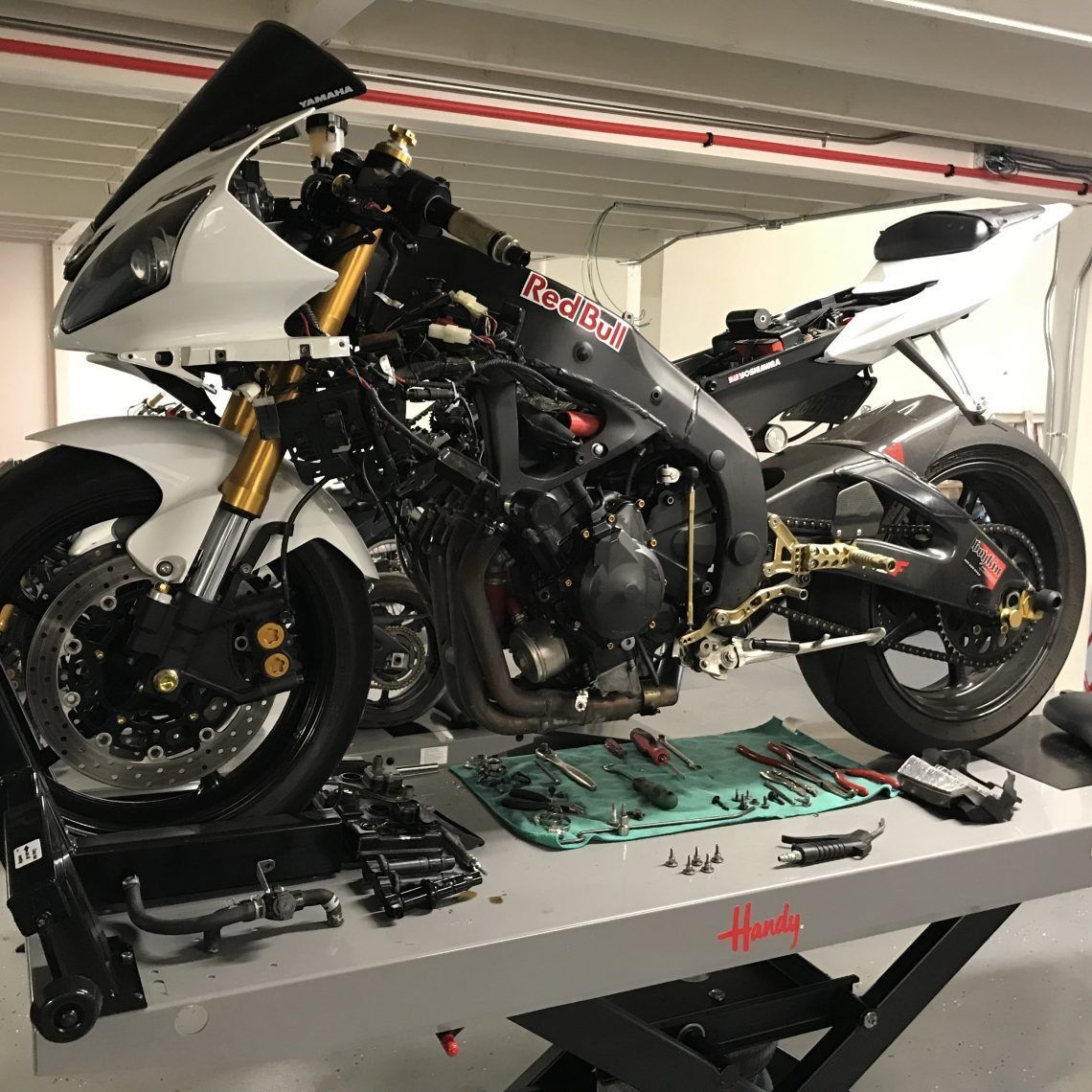 A motorcycle is sitting on a lift in a garage.