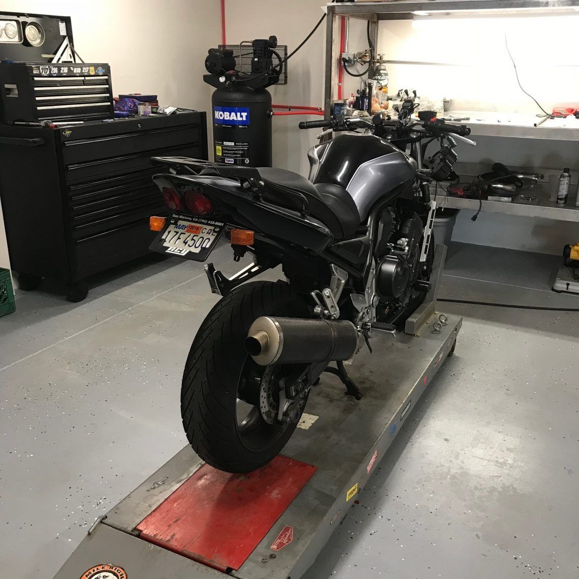 A motorcycle is parked on a ramp in a garage